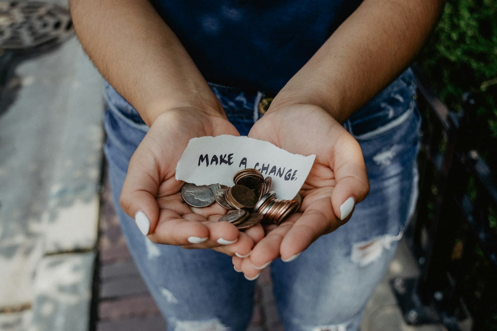 Hands holding coins with a Make a Change note, fundraising merch